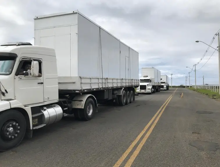 foto de caminhões transportando containers habitacionais para instalar a cozinha container
